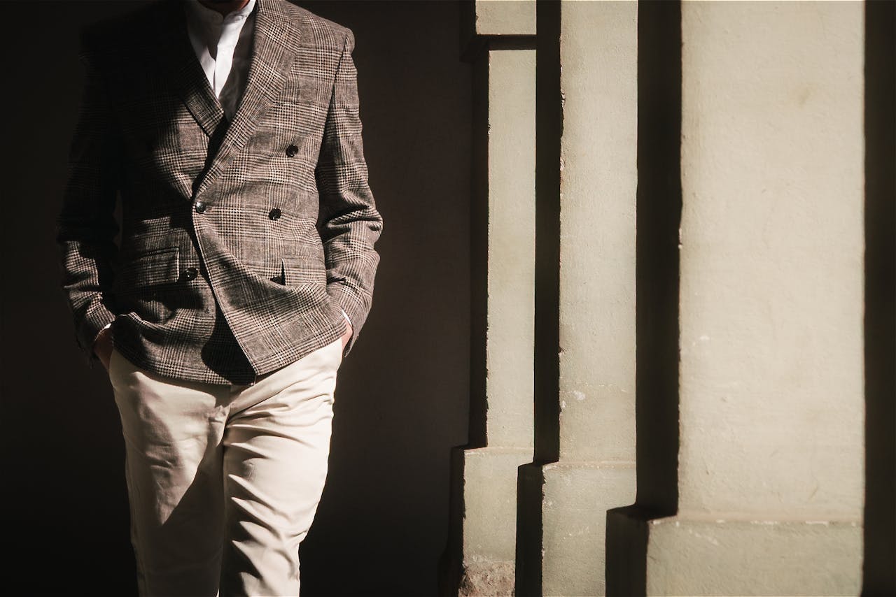 Sophisticated men's fashion with a plaid blazer and khakis, captured in striking sunlight and shadows.
