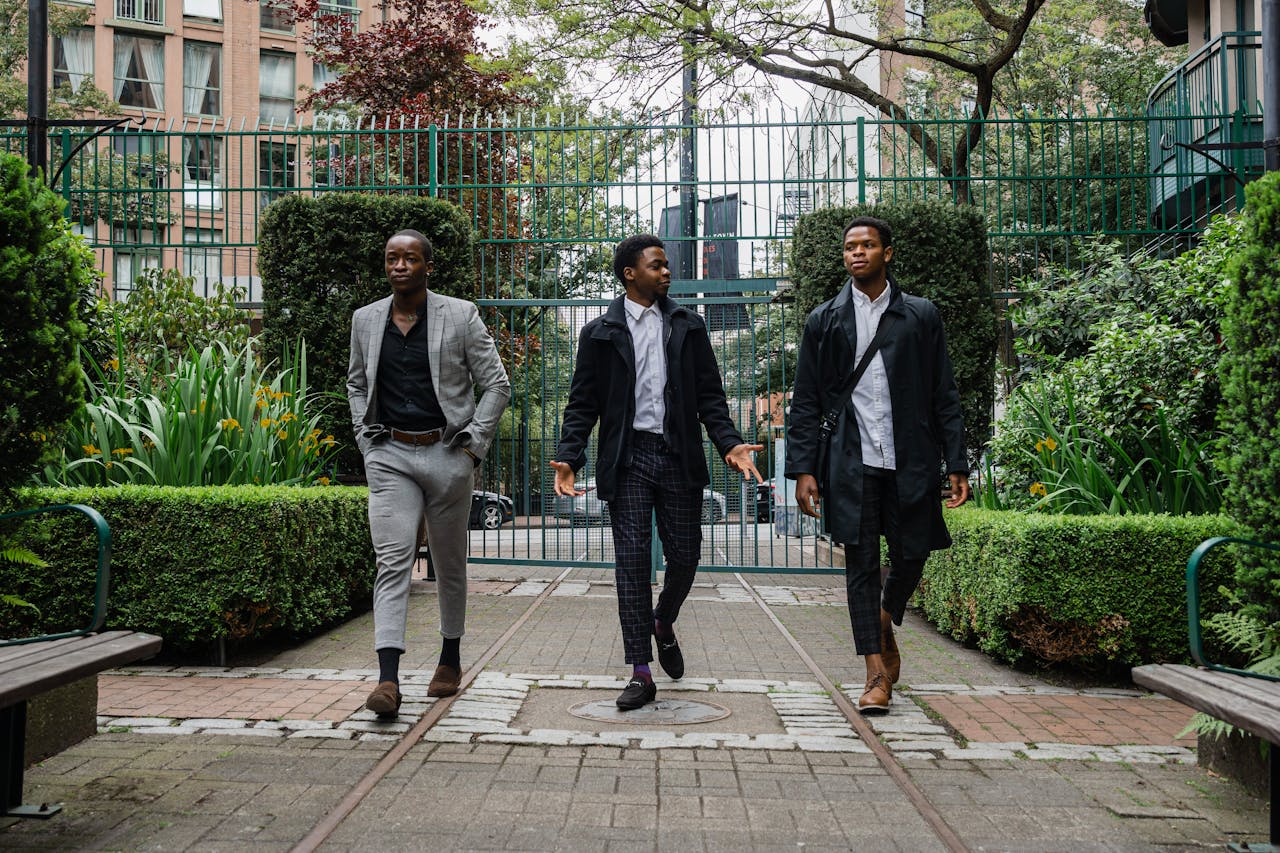ours-journey Three men in elegant suits are walking through an urban park, exuding confidence and style.